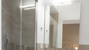 Une salle de bain moderne avec une douche en verre, un grand lavabo blanc et un miroir au-dessus du lavabo.