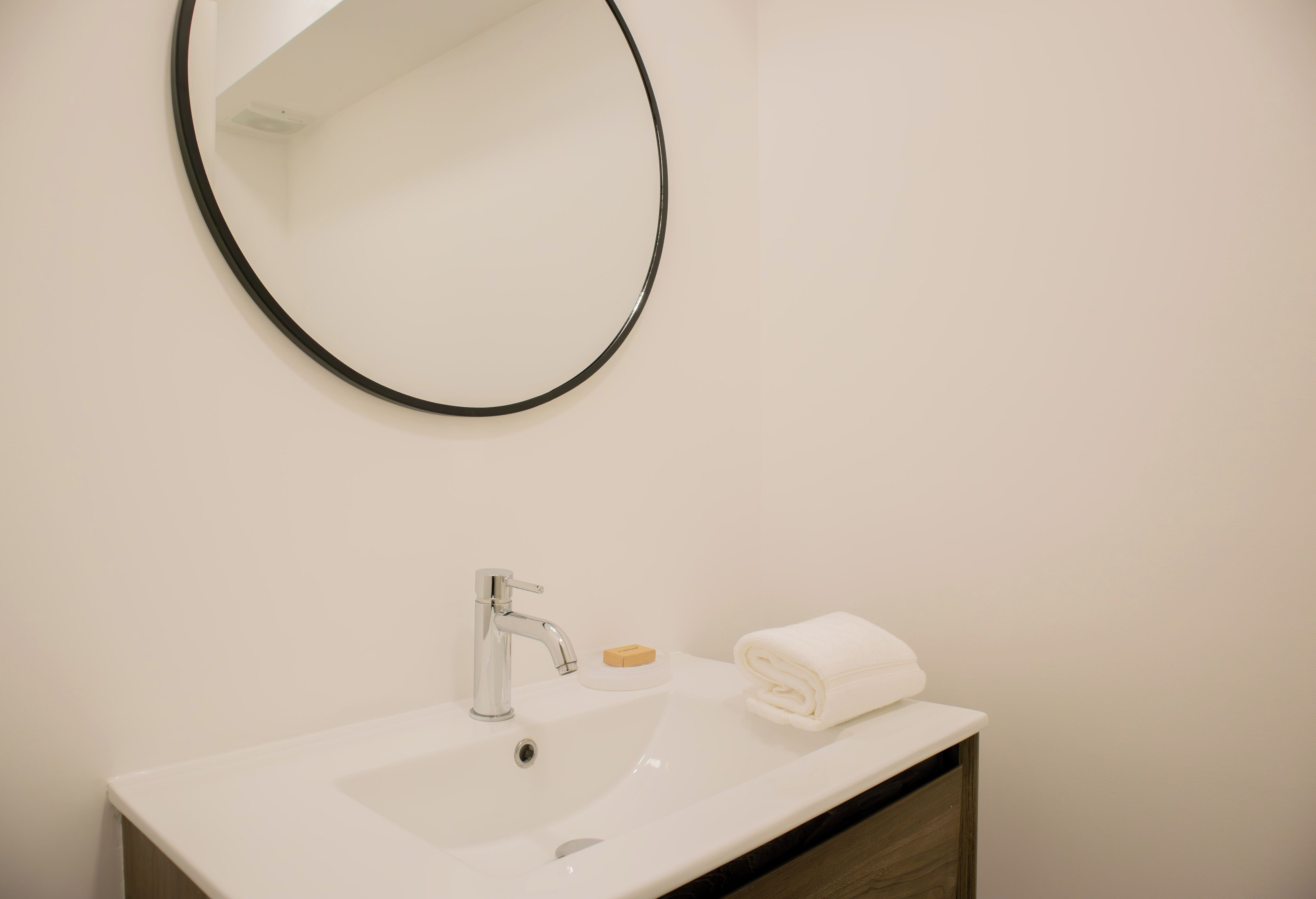 A bathroom with a white sink, a mirror, and a towel.