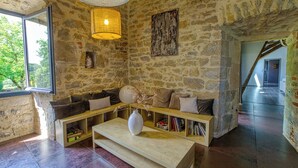 A stone-walled room with a wooden bench, a white vase, and a bookshelf. - Gite with swimming pool le Bervic (Sainte-Croix)