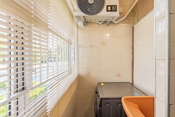 A compact bathroom with a window, a wall-mounted air conditioner, and a trash bin. - Apto c boa Localiza o Prox Centro pet Friendly (Jundiai)