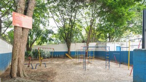 A playground with swings, slides, and climbing structures, surrounded by trees and a blue wall. - Apto c boa Localiza o Prox Centro pet Friendly (Jundiai)