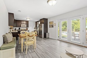 Eine moderne Küche mit dunklen Holzschränken, einem Edelstahlkühlschrank und einem Essbereich mit Holztischen und einem Tisch.