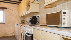 Une cuisine équipée d’un lave-linge, d’une cuisinière, d’un four à micro-ondes et de placards.