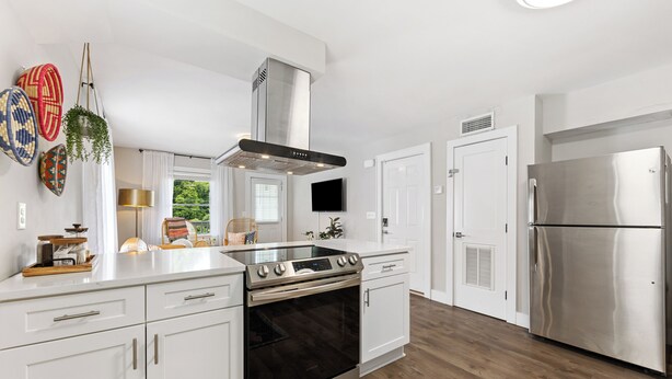 A modern kitchen with white cabinetry, a stainless steel range, and a built-in oven.