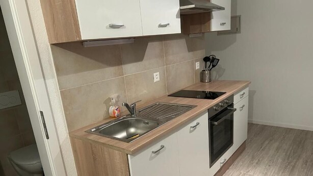 A modern kitchen with a sink, stove, and cabinets.