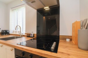 Una cocina moderna con tope de cocina por inducción negro, campana extractora de acero inoxidable y armarios de madera.