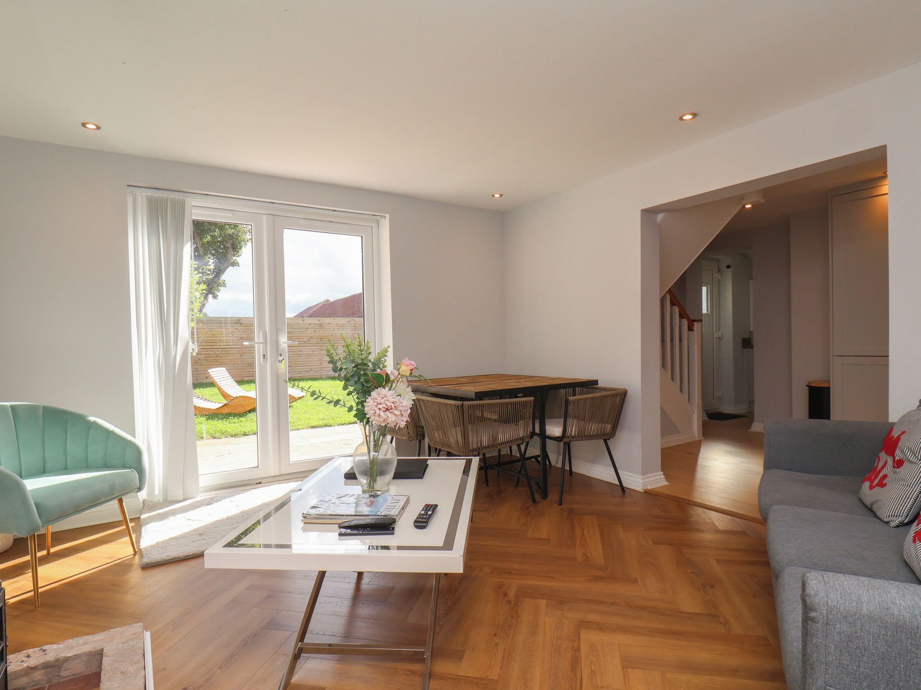 A spacious living area with a sofa, a coffee table with a vase, and a dining table with chairs.