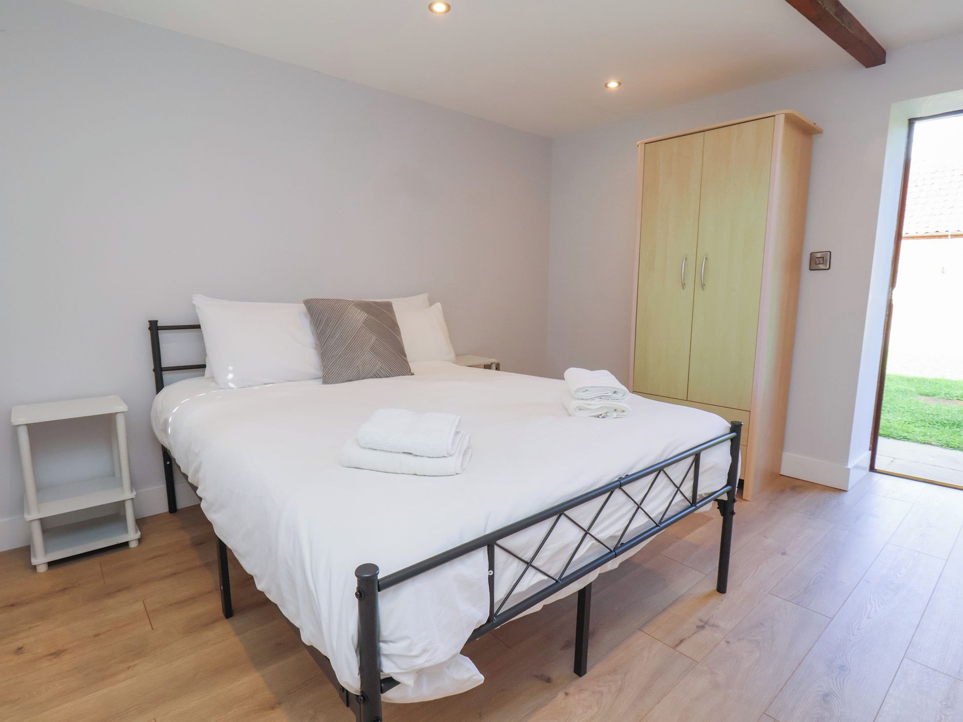 Un dormitorio con cama, mesita de noche, armario y vistas al exterior.