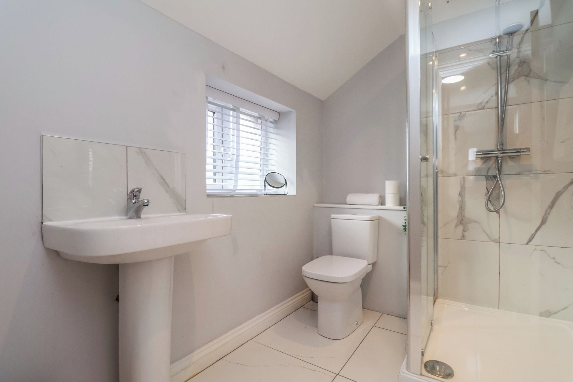 Une salle de bain équipée d’un lavabo, de toilettes et d’une douche à parois de verre.