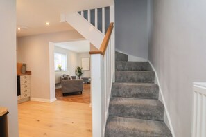 Un escalier avec des marches recouvertes de moquette et une rampe en bois menant à un palier.