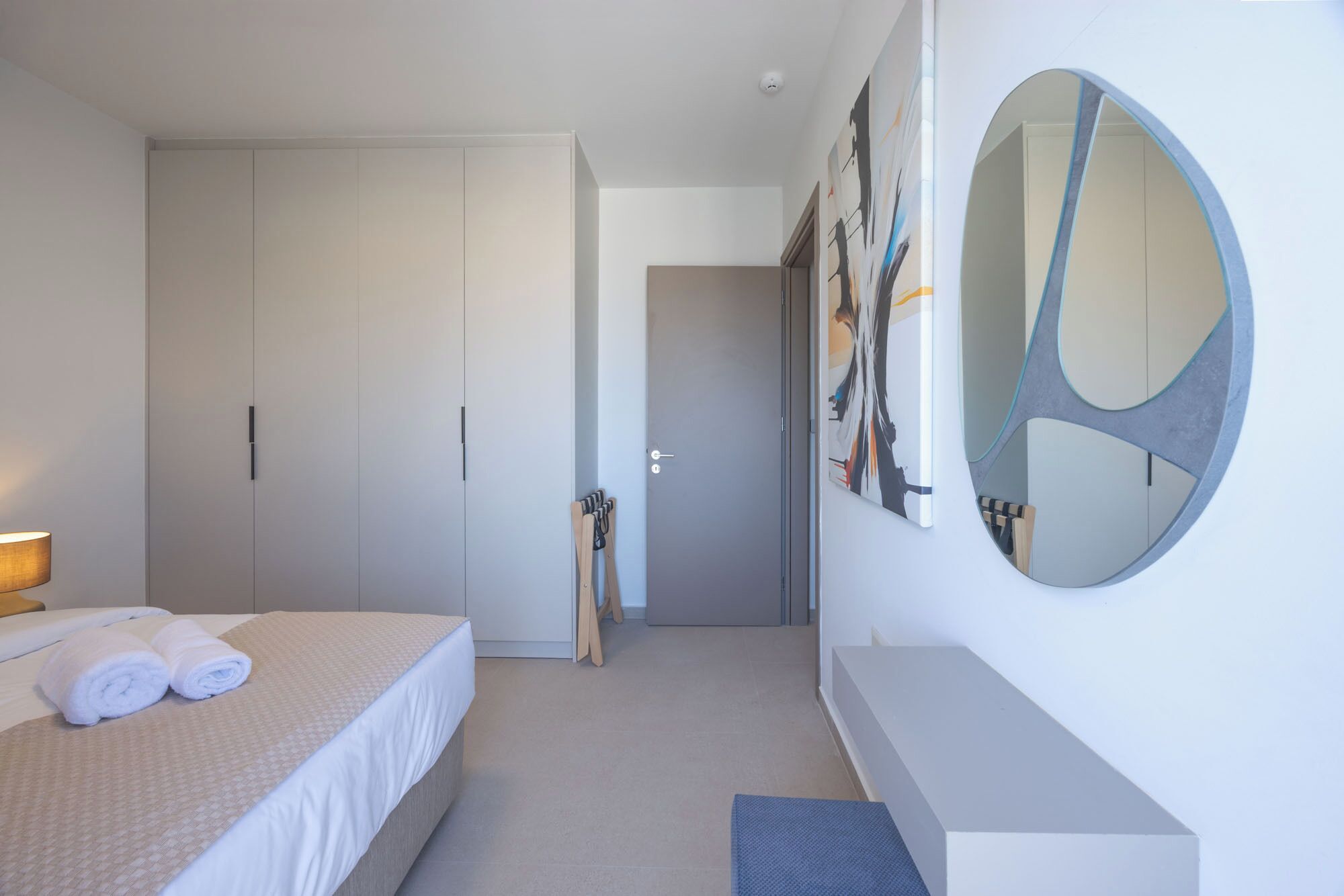 Une chambre d’hôtel moderne, équipée d’un lit, d’un grand miroir et d’une armoire.