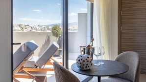 A modern room with a large window, a round table with a bottle and glasses, and two lounge chairs. - Sokio Attiki Hotel, Bw Premier Collection (Athens)
