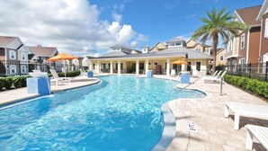 A swimming pool with lounge chairs and umbrellas, surrounded by residential-style buildings. - Contemporary Summerville resort home - 5 miles to Disney (Kissimmee)