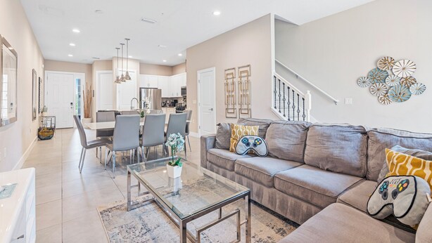 A modern living room with a sofa, coffee table, and dining area. - Contemporary Summerville resort home - 5 miles to Disney (Kissimmee)