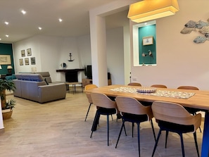 A modern living room with a sofa, dining table, and chairs, a TV, and a fireplace. - VILLA TIMOLEONTE - ADDAURA (Palermo)