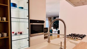 A modern kitchen with a built-in oven, a stainless steel faucet, and a glass cabinet with kitchenware. - VILLA TIMOLEONTE - ADDAURA (Palermo)