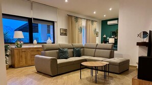 A modern living room with a sectional sofa, a small round coffee table, and a wooden cabinet. - VILLA TIMOLEONTE - ADDAURA (Palermo)