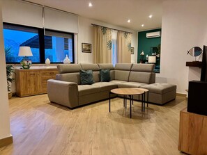 A modern living room with a sectional sofa, a small round coffee table, and a wooden cabinet. - VILLA TIMOLEONTE - ADDAURA (Palermo)