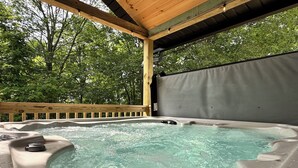 Un bain à remous doté d’une terrasse en bois et d’un toit abrité, le tout entouré d’arbres.