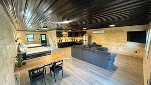 Un intérieur moderne avec un plancher en bois, un canapé, une table à manger avec des chaises et un coin cuisine.