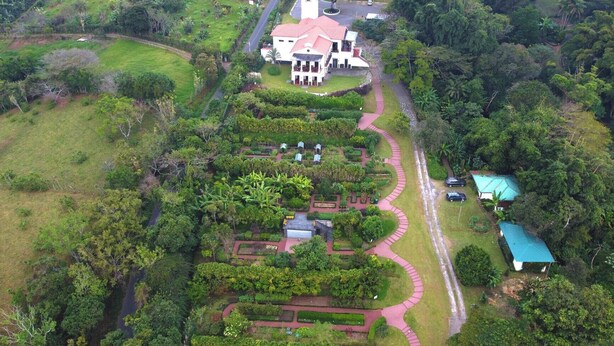 An aerial view of a large estate with a central building, surrounded by well-maintained gardens and pathways.