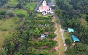 Vista aérea de una extensa propiedad con un edificio central, rodeada de jardines y senderos bien cuidados.