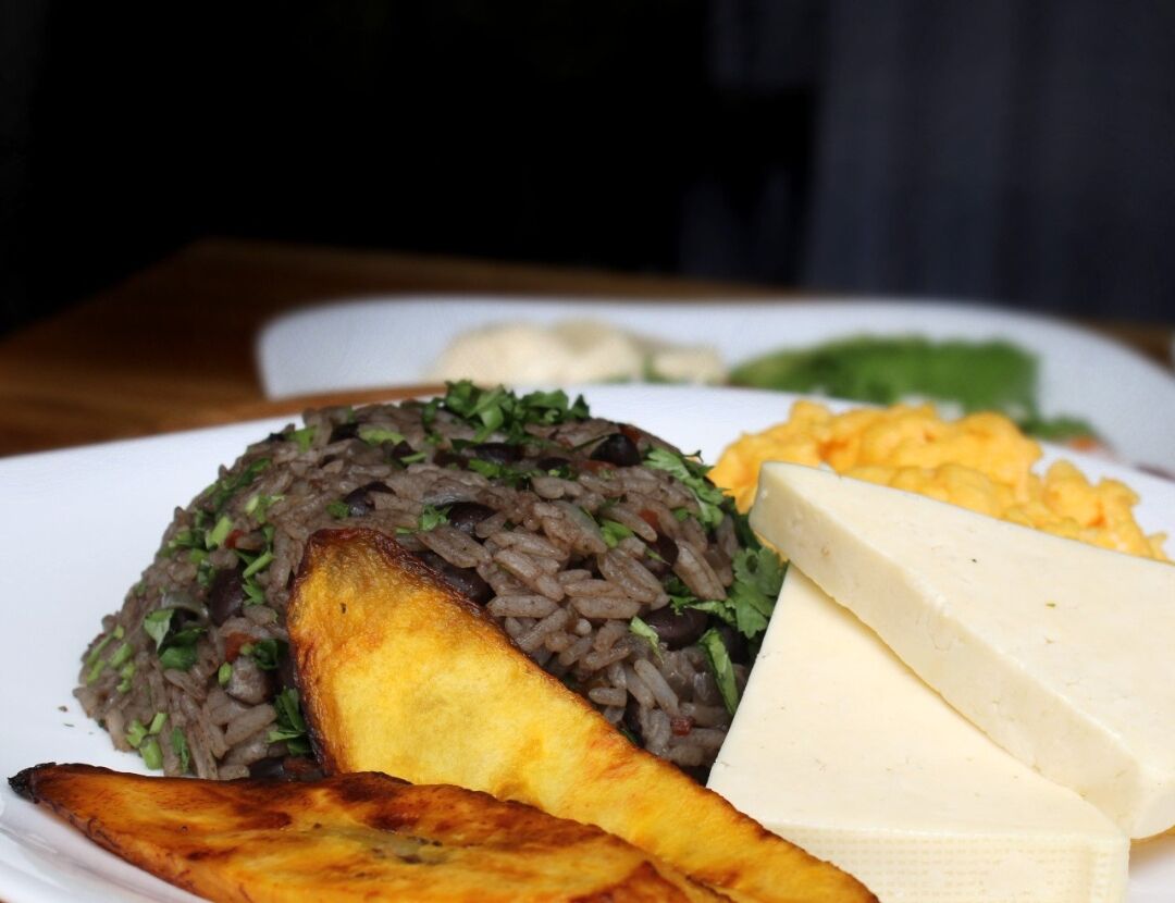 Un plato con arroz negro, plátanos fritos y queso.
