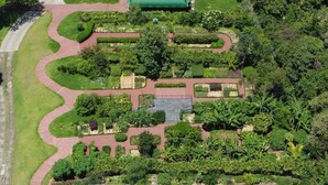 An aerial view of a landscaped garden with pathways, a central building, and surrounding greenery.