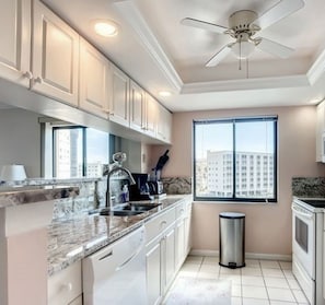 A modern kitchen with white cabinets, a granite countertop, a built-in oven, and a window with a city view. - Vista Bay in Fort Myers Beach (Fort Myers Beach)