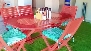 Una mesa de comedor de madera roja con sillas a juego, un florero en el centro y una pequeña planta sobre la mesa.