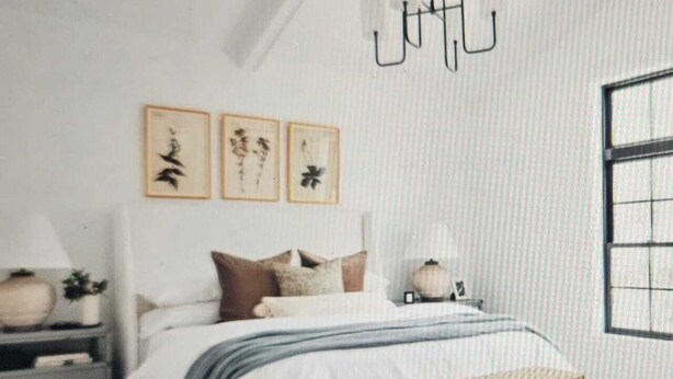 Un dormitorio con cama, mesitas de noche, un banco y decoración en la pared.