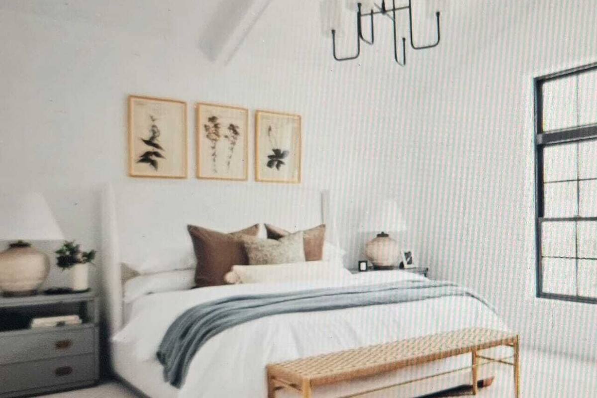 A bedroom with a bed, bedside tables, a bench, and wall art.