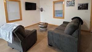 A living room with two grey sofas, a small round table, a ceiling fan, and wall-mounted TV and decorations. - Brand new 2-bedroom house in outskirts of Meridian with WiFi, AC (Meridian)