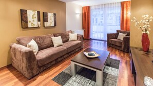 A modern living room with a brown sofa, a smaller armchair, a coffee table, and a vase of flowers.
