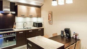A modern kitchen with a central island, built-in microwave, and stainless steel range hood.