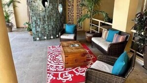 A covered outdoor seating area with wicker furniture, a red patterned rug, and a decorative wall with a circular cutout. - Scenic views in Downtown/Romantic Zone (Puerto Vallarta)