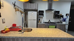 A modern kitchen with a granite countertop, stainless steel appliances, and pendant lighting.
