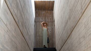 Une femme vêtue d’une robe verte descend un escalier étroit dont les murs sont en bois.