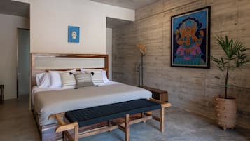Un dormitorio moderno con una cama de madera, un banco, una planta en maceta y un cuadro colgado en la pared.