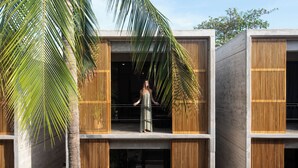 A modern building with a balcony, wooden slats, and a palm tree. - Hotel JILOO Petite Maison (Santa Maria Colotepec)