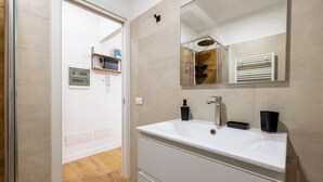 A modern bathroom with a white sink, a mirror, and a wooden floor.