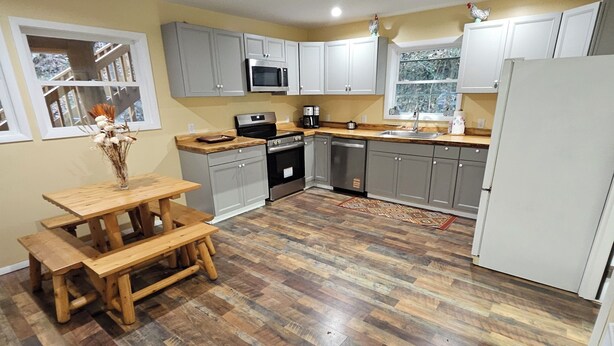 A kitchen with grey cabinets, a wooden table, and a refrigerator. - Charming barn loft in quaint Marshall (Marshall)