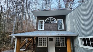 A two-story house with a covered porch, a front door, and a staircase leading to the upper level. - Charming barn loft in quaint Marshall (Marshall)