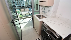 A modern kitchen with a large window, a dishwasher, and a sink. - Floripa Residence-Apartamento 3 quartos (Florianopolis)