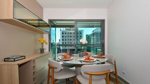 A modern dining area with a glass table, four chairs, and a built-in shelf. - Floripa Residence-Apartamento 3 quartos (Florianopolis)