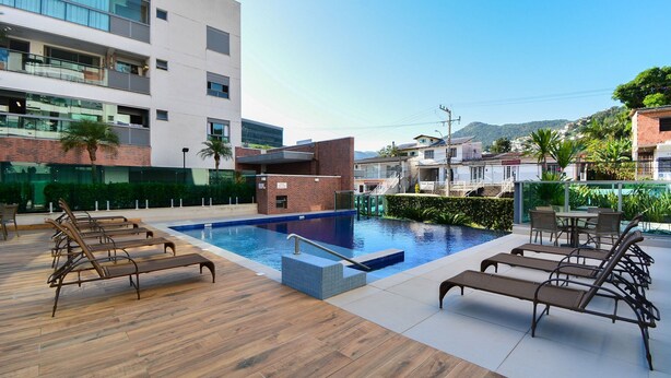 A rooftop pool area with lounge chairs, a small pool, and a view of surrounding buildings. - Floripa Residence-Apartamento 3 quartos (Florianopolis)