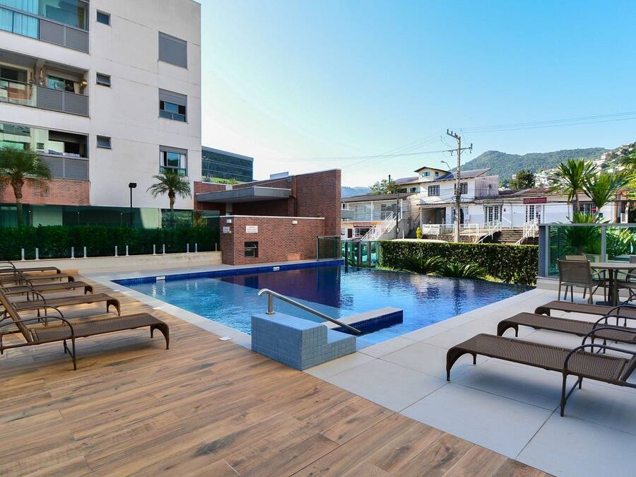 A rooftop pool area with lounge chairs, a small pool, and a view of surrounding buildings.