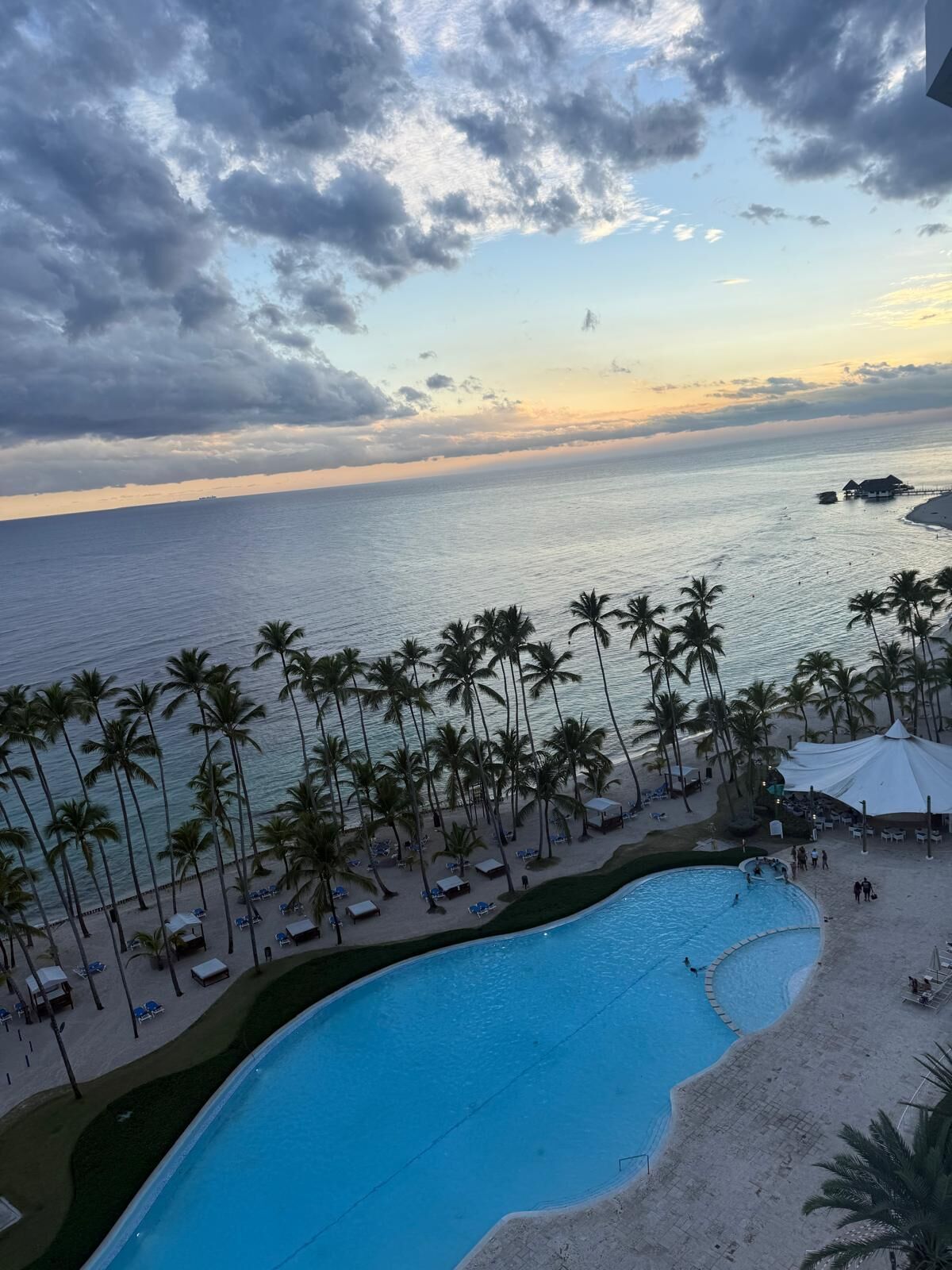 A resort with a pool, beach, and palm trees.