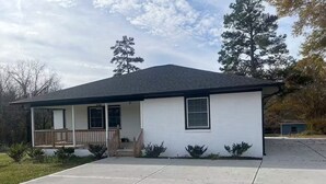 Une maison de plain-pied avec un porche à l’avant, un garage et une allée.