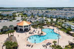 A residential area with a swimming pool surrounded by houses and palm trees.